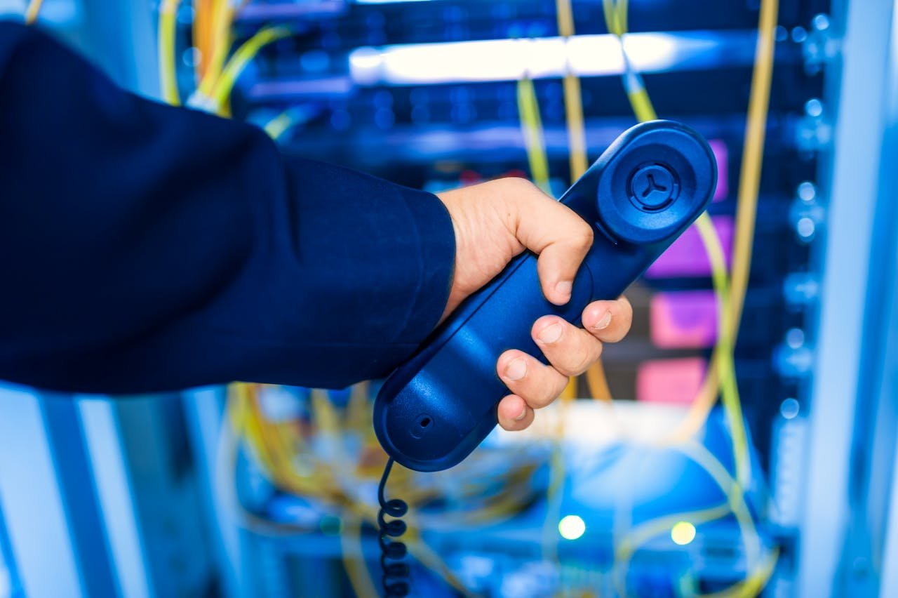 client-satisfaction-img Close-up of a hand holding a telephone receiver in a server room emphasizing technology.